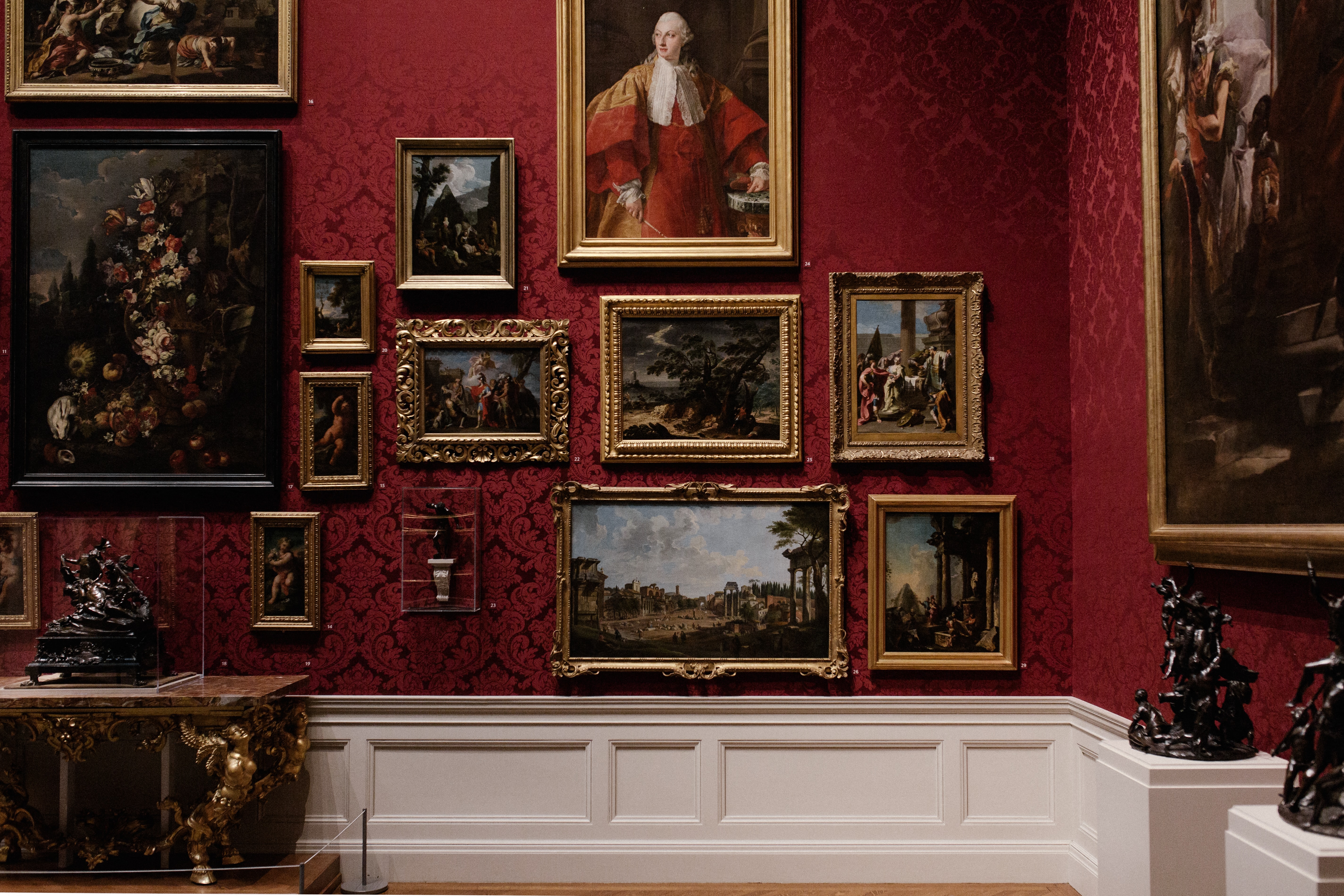 Photographie d'un mur d'une galerie de musée avec différentes toiles accrochées.