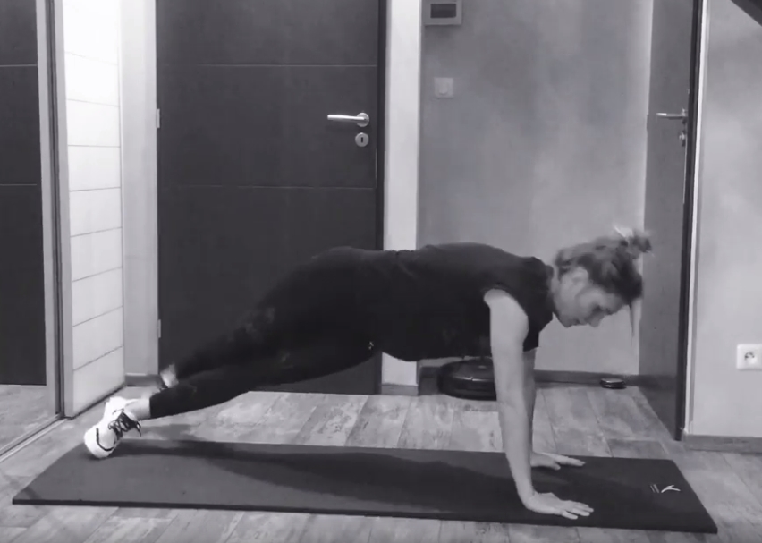 Photographie extraite d'une vidéo proposant un exercice de fitness sur laquelle figure une femme en position de pompe sur un tapis.