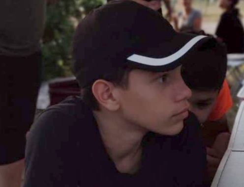 Portrait d'un jeune garçon de profil portant une casquette noire et blanche.